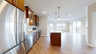 Located at 3800 Jeffers Pky NW in Prior Lake, MN, this well-appointed 2-bedroom, 3-bathroom residence offers a thoughtfully designed single-floor layout. The open-concept kitchen and living area serves as the heart of the home, featuring rich warm-toned cabinetry, a white subway tile backsplash, stainless steel appliances, and a center island with a light quartz countertop. Pendant lighting accents the island, while recessed lighting and large windows flood the space with natural light. Light-toned hardwood-style flooring runs throughout the main living areas, complementing the neutral color palette. The living room extends to a private balcony through a sliding glass door, offering expansive outdoor views of the surrounding landscape. The bedrooms are carpeted for comfort and feature large windows that frame scenic views, providing a bright and airy feel. The primary bedroom includes a walk-in closet with built-in shelving. The bathrooms are clean and functional, with one featuring a full soaking tub and shower combination. Crown molding and crisp white trim add a refined finishing touch throughout the space, contributing to an overall ambiance that is modern, comfortable, and move-in ready.