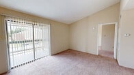 Located in Texas City, TX, this one-bedroom, one-bathroom unit offers a practical and comfortable single-floor layout. The living room is generously sized, featuring soft wall-to-wall carpeting and large vertical-blind-covered sliding glass doors that allow natural light to fill the space while providing access to the outdoors. The kitchen is positioned in an open-concept style, separated from the living area by a peninsula breakfast bar with a light-toned countertop. The kitchen includes white cabinetry, a range, refrigerator, and hardwood-style flooring, with a pantry providing additional storage. A hallway connects the main living area to the private quarters. The spacious primary bedroom features plush carpeting, a ceiling fan with light fixture, and a window that brings in natural light. It is complemented by two closets, including a walk-in closet outfitted with dual hanging rods and shelving for generous storage capacity. The bathroom includes a full tub and shower combination with clean white tile surround and hardwood-style flooring. Neutral tones and a straightforward layout throughout the unit create a functional and move-in-ready living environment.