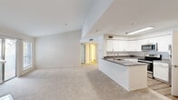 This single-floor residence offers a thoughtfully designed layout encompassing two bedrooms and four bathrooms. The open-concept living and kitchen area serves as the heart of the home, featuring vaulted ceilings that lend a sense of spaciousness beyond the unit's footprint. The kitchen is outfitted with white shaker-style cabinetry, granite-topped counters, stainless steel appliances including a range, microwave, and refrigerator, and a peninsula with a built-in sink that provides both additional workspace and a natural division from the carpeted living area. A tile fireplace anchors the living room, which benefits from multiple sliding glass doors that invite natural light and outdoor access.

Both bedrooms are carpeted and generously proportioned, with the primary bedroom featuring a walk-in closet equipped with wire shelving on both sides. The primary bathroom showcases an angled, wrap-around granite vanity with dual sinks, white cabinetry, and well-lit mirrors. Additional bathrooms include a tiled tub-shower combination. Wood-look flooring is featured in the kitchen and bathroom areas. The unit also includes a dedicated laundry space and a private entrance, completing a practical and cohesive floor plan.