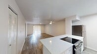 This single-floor, 2-bedroom, 2-bathroom unit spans 870 square feet and features a clean, modern aesthetic with wood-look luxury vinyl plank flooring carried consistently throughout every room. The open kitchen and living area combination provides a functional, connected layout. The kitchen is equipped with stainless steel appliances, including a refrigerator and dishwasher, white cabinetry, and light stone countertops. The spacious living room offers neutral walls, recessed ventilation, and ample room for various furniture arrangements. Both bedrooms are well-proportioned — the primary bedroom measures 150 square feet — and each features a ceiling fan with light fixture and natural light from windows fitted with horizontal blinds. One bedroom includes a mirrored sliding-door closet, while the other offers access to a dedicated walk-in closet outfitted with wire shelving systems for organized storage. The two full bathrooms each feature a tub-shower combo with a surrounding white surround, toilet, and a white vanity with sink, accented by brushed nickel or brass hardware. The unit's neutral color palette and consistent flooring create a cohesive, move-in-ready environment throughout.