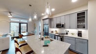 This single-floor residence showcases a thoughtfully designed open-concept layout with modern finishes throughout. The kitchen serves as a central highlight, featuring gray shaker-style cabinetry, granite countertops, and a generously sized island with an undermount sink. Stainless steel appliances, including a gas range, built-in microwave, and French door refrigerator, are complemented by a white subway tile backsplash. Pendant lighting with glass bell-shaped fixtures adds a stylish focal point above the island.

The living area offers access to a private balcony through full-height glass doors, with hardwood flooring and a ceiling fan enhancing the comfortable atmosphere. The primary bedroom is a standout space, boasting dramatic floor-to-ceiling windows on two walls that frame sweeping urban views and flood the room with natural light.

Two bathrooms are finished with granite-topped gray vanities and tile flooring. The primary bath includes a walk-in glass shower, while the secondary bath offers a soaking tub with a tiled surround and direct access to a walk-in closet. A dedicated in-unit laundry room with side-by-side washer and dryer and overhead cabinetry adds practical convenience to the space.