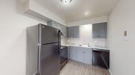 This two-bedroom, one-bathroom unit in Saginaw, Michigan offers a functional and thoughtfully updated single-floor layout. The kitchen is a standout feature, showcasing gray shaker-style cabinetry, granite-look countertops, wood-look luxury vinyl plank flooring, and a full suite of black appliances including a refrigerator, range, and dishwasher. Ample upper and lower cabinet storage makes this kitchen as practical as it is attractive.

The living area is generously sized, featuring plush neutral carpeting, baseboard heating, and multiple windows fitted with vertical blinds that allow for natural light. The open, airy feel of the space is enhanced by clean white walls and a straightforward layout that transitions easily between rooms.

Both bedrooms are comfortably proportioned with soft carpeting, neutral tones, and windows providing natural light. One bedroom features decorative wainscoting wall paneling, adding a subtle design touch.

The bathroom is clean and modern, with tile-surround tub and shower combination, wood-look flooring, a white vanity, and a window for ventilation and natural light. The overall ambiance of this unit is bright, neutral, and move-in ready, offering a comfortable living environment in a practical, well-organized floor plan.