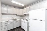 Located at 190 E 500 S in Salt Lake City, Utah, this one-bedroom, one-bathroom unit offers a well-organized single-floor layout with a practical mix of finishes and functional living spaces. The combined kitchen and living room serves as the heart of the unit, where wood-look flooring flows through the kitchen area. The kitchen is equipped with white cabinetry, a full-size refrigerator, electric range, and ample counter space, all beneath a textured ceiling with overhead lighting. A wall-mounted mini-split unit provides climate control in the living area, which features plush carpeting and a wide window with vertical blinds that draw in natural light and offer views of the surrounding cityscape. The generously sized primary bedroom is carpeted and bright, centered around a wide window dressed with vertical blinds that continue the unit's cohesive aesthetic. The bathroom includes a single-sink vanity with a mirrored medicine cabinet, a combined shower and bathtub with safety grab bars, and wood-look flooring. Two hallways connect the spaces efficiently. The unit's neutral color palette, textured ceilings, and consistent finishes throughout create a clean and functional living environment.