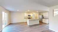 Located at 6302 Fescue Rd in Castle Hayne, NC, this two-story home offers four bedrooms, five bathrooms, and a thoughtfully designed layout spread across two generous floors. The main level features an open-concept living, dining, and kitchen area anchored by wood-look flooring and an abundance of natural light from large windows and a sliding glass door. The kitchen is equipped with white shaker cabinetry, granite countertops, stainless steel appliances, and a central island with a sink — ideal for both everyday living and entertaining. A pantry provides additional storage convenience. The upper floor is the larger of the two levels and hosts the bedrooms, including a spacious primary suite complete with a private en-suite bathroom featuring a glass-enclosed walk-in shower, a separate water closet, and a generous walk-in closet with wire shelving. Additional bedrooms are well-proportioned, each with closet space. A bonus room adds flexibility for a home office, playroom, or media space. The dedicated laundry room includes side-by-side washer and dryer hookups with overhead shelving. A full garage with an automatic opener completes the home, offering secure parking and extra storage. Throughout, the home maintains a clean, neutral palette with consistent flooring and modern fixtures.