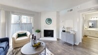 Located at 270 El Dorado Blvd in Houston, TX, this single-floor, one-bedroom, two-bathroom residence offers a thoughtfully designed layout that maximizes every square foot of its compact footprint. The living room serves as the heart of the home, showcasing rich hardwood-style flooring, a white brick wood-burning fireplace as a striking focal point, and a sliding glass door that floods the space with natural light and opens onto a private balcony. The galley-style kitchen is both stylish and functional, featuring white shaker cabinetry with brushed nickel hardware, a grey tile backsplash, light countertops, and black appliances. An adjacent pantry provides valuable additional storage. The spacious bedroom is finished with plush carpet, a ceiling fan, and a dedicated closet, offering a comfortable and serene retreat. Two full bathrooms serve the unit, one featuring a tub-shower combination with clean white tile, and the other providing a wide vanity with ample cabinetry — a stacked in-unit washer and dryer is also conveniently located nearby. A connecting hallway ties the rooms together seamlessly. The overall aesthetic is light, neutral, and modern throughout.