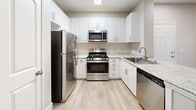 This 640-square-foot, one-bedroom, one-bathroom apartment at 25335 Alessandro Blvd in Moreno Valley, CA offers a well-designed single-story layout that maximizes its space efficiently. Wood-style flooring runs throughout the entire unit, lending a cohesive and modern aesthetic.

The open-concept kitchen and living area form the heart of the unit. The kitchen features white shaker-style cabinetry, granite-look countertops, a peninsula with a built-in sink, and a full suite of stainless steel appliances including a gas range, microwave, dishwasher, and refrigerator. A skylight above the kitchen provides an abundance of natural light.

The living area is bright and open, with sliding glass doors leading to a private balcony with outdoor views, making the space feel larger than its footprint.

The 150-square-foot bedroom is a comfortable retreat, equipped with a ceiling fan, multiple windows for natural light, and direct access to a spacious walk-in closet featuring wire shelving for ample storage. The bathroom includes a full tub-shower combination with brushed nickel fixtures.

A neutral gray color palette throughout, combined with clean white trim, creates a bright and inviting ambiance across the entire unit.