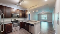 Located at 4025 Pier Light Dr in Wyoming, MI, this single-floor, 2-bedroom, 2-bathroom residence offers a thoughtfully designed open-concept layout. The kitchen is a standout feature, showcasing rich dark-wood cabinetry, granite countertops, stainless steel appliances—including a refrigerator, electric range, microwave, and dishwasher—and a peninsula with pendant lighting that flows seamlessly into the living area. The living room is bright and airy, highlighted by a tray ceiling with a ceiling fan, large windows that bring in abundant natural light, and gleaming hardwood-style flooring throughout. Both bedrooms are carpeted for comfort, with the spacious primary bedroom featuring direct access to a walk-in closet with wire shelving and its own private bathroom. The bathrooms are finished with granite-topped dark-wood vanities and wood-look flooring; one includes a soaking tub with a curved shower rod. A dedicated laundry room houses a full-size washer and dryer. The hallway connects all areas efficiently, and two closets provide ample storage. Soft blue-gray walls throughout lend a calm, cohesive aesthetic to this well-finished residence.