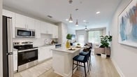 Located at 350 Bay Laurel Dr in St. Augustine, FL, this well-appointed 2-bedroom, 2-bathroom residence offers a thoughtfully designed single-level layout. The open-concept kitchen and living area serves as the heart of the home, where crisp white shaker cabinetry, granite countertops, and a full suite of stainless steel appliances — including a refrigerator, range, and microwave — create a sleek, functional space. A central kitchen island with seating provides an ideal spot for casual dining or entertaining. Light wood-style flooring flows seamlessly throughout the main living areas, enhancing the bright, airy atmosphere. The living room is bathed in natural light through large windows and a glass door, complemented by a ceiling fan and ample space for relaxing. Both bedrooms feature plush carpeting and direct access to a dedicated closet, with the primary bedroom offering an ensuite bath. Each bathroom is finished with wood-look tile flooring, granite vanity tops, and a tiled tub-shower combination. The neutral, warm color palette throughout the residence creates a cohesive and inviting ambiance, making this St. Augustine home a comfortable and stylish retreat.