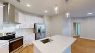 Located at 208 Windfall Way in Myrtle Beach, SC, this single-story home offers a thoughtfully designed layout across three bedrooms and two bathrooms. The open-concept kitchen and living area serves as the heart of the home, showcasing crisp white cabinetry, a subway tile backsplash, stainless steel appliances including a French door refrigerator and electric range with a stainless hood, and a large center island topped with speckled quartz countertops. A double undermount sink and stylish glass pendant lights complete the kitchen's polished aesthetic. Warm hardwood-style flooring extends throughout the home, complementing the neutral wall tones.

The bedrooms are bright and functional, with multiple windows fitted with blinds allowing natural light while maintaining privacy. The primary bedroom features a ceiling fan and access to a walk-in closet equipped with built-in wire shelving. The bathrooms include a clean, modern walk-in shower with a sliding glass door. A dedicated laundry room accommodates a full-size washer and dryer with overhead wire shelving for additional storage. The overall ambiance is clean, contemporary, and move-in ready.