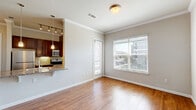Located in Little Elm, TX, this well-appointed one-bedroom, one-bathroom residence offers a thoughtfully designed single-floor layout. Warm wood-look flooring flows consistently throughout the space, complemented by crown molding and neutral gray walls that create a clean, cohesive aesthetic.

The open-concept living, dining, and kitchen area serves as the heart of the home. The living and dining space is bright and airy, drawing in natural light through large windows with outdoor views. A track lighting fixture adds additional illumination. The galley-style kitchen is efficiently designed with rich, dark wood cabinetry extending to the ceiling, granite countertops, a tile backsplash, and stainless steel appliances including a refrigerator, range, and microwave. A breakfast bar provides casual seating and connects the kitchen to the living area.

The bedroom is a comfortable, well-lit retreat with a window overlooking the outdoors, crown molding, and access to a dedicated walk-in closet outfitted with multi-level shelving rods for organized storage. The bathroom features a granite-topped vanity with dark cabinetry, a soaking tub with tile surround and glass sliding doors, and wood-look flooring. Additional conveniences include a pantry and in-unit laundry.