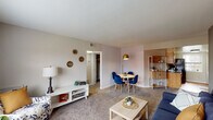 This single-floor residence offers a thoughtfully arranged layout that balances comfort and functionality. The open living and dining area serves as the heart of the home, featuring plush carpet flooring, neutral-toned walls, and a charming accent wall with a subtle herringbone-patterned wallpaper. The living space comfortably accommodates both a seating area and a dedicated dining nook, creating a versatile environment for relaxing and entertaining. A built-in shelving unit adds both storage and visual interest to the space.

The galley-style kitchen is efficiently designed with warm honey-toned cabinetry, dark granite-style countertops, and black appliances including a refrigerator, stove, and dishwasher. A window above the counter allows natural light to brighten the workspace, while hardwood-style flooring adds a clean, polished finish.

The bedroom is a calm and restful retreat, featuring carpet flooring, soft gray walls, and ample space for a full furniture arrangement. The room is well-proportioned, offering a welcoming atmosphere enhanced by warm accent decor.

The full bathroom is finished with hardwood-style flooring, a warm wood-toned vanity, and a tub-shower combination with a bright window that brings in natural light, completing this well-rounded and move-in-ready home.