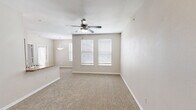 Located at 18211 Bulverde Rd in San Antonio, TX, this well-designed one-bedroom, one-bathroom residence offers a thoughtful single-floor layout that maximizes functionality and comfort. The open-concept kitchen and living area serves as the heart of the unit, where a peninsula counter with granite-style countertops provides both workspace and a casual dining option. The kitchen is equipped with dark espresso cabinetry, a tile mosaic backsplash, black appliances, and track lighting overhead, all set atop warm hardwood-style flooring that adds a classic touch. The living area transitions seamlessly from the kitchen, offering a welcoming and versatile space. The generously sized bedroom features plush carpeting, a ceiling fan with light fixture, and multiple windows with blinds that allow natural light to fill the room. The bedroom connects directly to a walk-in closet outfitted with wire shelving for ample storage. The full bathroom is appointed with dark wood vanity cabinetry, granite-style countertops, a large mirror, and a tub/shower combination with tiled surround, all over easy-to-maintain hardwood-style flooring. Neutral tones and clean finishes throughout lend the space a calm, move-in-ready ambiance.