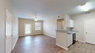 Located at 3500 E McKinney St in Denton, TX, this single-floor unit offers three bedrooms and three full bathrooms within a well-organized, efficient layout. The open-concept living and dining area is bright and welcoming, featuring warm wood-style flooring, neutral wall tones, and a ceiling fan. Large windows and a glass-paned exterior door allow natural light to fill the space, creating an airy atmosphere. The kitchen flows seamlessly from the living area via a peninsula counter with granite-style countertops, white cabinetry, and black appliances including a refrigerator, range, and dishwasher. A hallway connects the main living area to the three bedrooms, each finished with wood-style flooring, ceiling fans, and windows fitted with blinds for privacy and light control. One bedroom includes a closet with double panel doors. All three bathrooms feature granite-style vanity countertops, full tub-shower combinations with white tile surrounds, and hardwood-style flooring. The consistent neutral color palette and matching finishes throughout lend the space a cohesive, clean aesthetic. The straightforward single-level floor plan provides practical, comfortable living for a range of occupants.