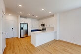 Located at 113 Hominy Ridge Ct in Asheville, NC, this efficiently designed single-floor home offers a thoughtful layout across its well-utilized footprint. The open-concept kitchen and living area serves as the heart of the home, showcasing a striking two-tone cabinetry design with crisp white upper cabinets and slate-blue lower cabinets, complemented by a classic white subway tile backsplash. A peninsula with a white quartz countertop provides additional prep and dining space. Stainless steel appliances, including a French door refrigerator with ice and water dispenser, a range, built-in microwave, and dishwasher, complete the kitchen. Light hardwood flooring runs seamlessly throughout the entire home, adding warmth and continuity. The living area is bright and welcoming, with large windows and a glass door that invite abundant natural light and offer outdoor views. The bedroom is a comfortable retreat, featuring a glass door leading to a private outdoor space, multiple windows, and access to two closets, including a walk-in with wire shelving. The bathroom includes a tiled tub-shower combination, a white vanity, and wood-tone flooring. A dedicated laundry area and hallway round out this clean, modern home.