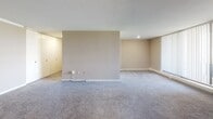 Located at 660 Boas St in Harrisburg, PA, this single-floor unit offers a well-organized layout designed for comfortable urban living. The kitchen is outfitted with white cabinetry, granite-style countertops, a gas range, and wood-look flooring, providing a clean and functional workspace. A pass-through counter connects the kitchen to the adjacent living areas, enhancing the open feel of the floor plan. The carpeted living and dining areas are generously sized and benefit from large floor-to-ceiling windows that flood the space with natural light and frame views of the Harrisburg cityscape, including notable government buildings. A sliding glass door in the living area leads to an outdoor balcony, extending the living space outward. The bedroom is spacious, featuring plush carpet, neutral-toned walls, and an expansive built-in closet system with multiple bifold doors offering abundant storage. Two bathrooms serve the unit: one features yellow ceramic tile wainscoting with a stand-up shower enclosed in sliding glass doors and wood-look flooring, while the other includes gray tile wainscoting, a wide vanity with a mirror and bar lighting, and a light countertop surface. Throughout the unit, recessed lighting, baseboard heating, and clean white trim contribute to a tidy, move-in-ready aesthetic.