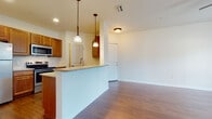 Located at 5515 First Ave E in Bradenton, Florida, this single-story unit offers a well-designed open-concept living space with a clean, functional layout. Rich hardwood-style flooring flows throughout the main living and dining areas, complementing the neutral white walls and creating a warm, cohesive aesthetic.

The kitchen is positioned at the heart of the unit, anchored by a peninsula with a granite-style countertop and an undermount sink. Warm-toned wood cabinetry lines the walls, providing generous storage, while stainless steel appliances—including an electric range, over-the-range microwave, and dishwasher—add a modern, polished finish. Pendant lighting above the peninsula enhances both function and style.

The open living and dining areas benefit from natural light through slatted windows, with a ceiling fan adding comfort to the main living space. A pendant light fixture marks the dining area, which flows seamlessly from the kitchen.

Bedrooms feature plush carpeting for comfort and are generously proportioned with ample wall space. The bathroom is finished with tile flooring, a wood-cabinet vanity with a granite-topped sink, a framed mirror, and a full soaking tub with tiled surround, offering a practical and tidy design throughout.