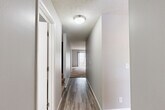 Located in Omaha, Nebraska, this multi-level home spans three floors and offers a practical, well-organized layout designed for comfortable everyday living. The main level features a combined dining room and kitchen alongside a spacious living room finished with plush carpeting and a sliding glass door that invites natural light and outdoor views. Neutral gray walls and textured ceilings carry throughout, lending a cohesive and understated aesthetic to the home.

The upper level houses two carpeted bedrooms, each equipped with ceiling fans and windows fitted with blinds for light control. The generously sized primary bedroom provides a comfortable personal retreat. Two full bathrooms serve the home, both finished with wood-look luxury vinyl flooring, white vanities with light stone-style countertops, and tub-shower combinations with brushed nickel hardware.

Hallways with durable hardwood-style flooring connect the rooms efficiently, and six closets distributed across the home ensure exceptional storage capacity. The lower level features an unfinished basement with painted concrete floors, painted cinder block walls, exposed wood-beam ceilings, and small egress windows — offering significant potential for additional storage or future finishing. Four staircases facilitate smooth movement between all three levels of this thoughtfully laid-out Omaha home.