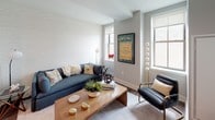 Located at 534-536 Broad Street in Newark, NJ, this well-appointed one-bedroom, one-bathroom residence offers a thoughtfully designed single-floor layout with modern finishes throughout. The open-concept kitchen is a standout feature, equipped with stainless steel appliances including a refrigerator, electric range, microwave, and dishwasher. Light-toned flat-panel cabinetry lines the walls, complemented by white quartz countertops, a subway tile backsplash, and warm hardwood-style flooring. A granite-topped kitchen island with bar seating provides additional dining and prep space. The living area is bright and welcoming, benefiting from multiple windows that invite natural light and offer city views. Subtle textured accent walls add visual depth and a contemporary touch carried throughout the unit. The bedroom is a tranquil retreat, featuring the same textured wall treatment, hardwood-style flooring, a natural light-filled window, and a double-door closet offering ample storage. The bathroom is finished with herringbone-patterned tile flooring, marble-look wall tile, a wood-toned vanity with an integrated sink, and a large mirror with overhead lighting. Clean lines and a neutral palette unify the space, creating a cohesive and modern urban living environment.