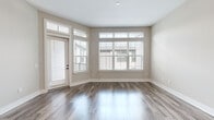 Located at 10970 Bell Rd in Johns Creek, GA, this single-floor residence offers a thoughtfully designed one-bedroom, two-bathroom layout that maximizes comfort and functionality. The open-concept living and kitchen area serves as the heart of the home, featuring rich hardwood-style flooring, neutral warm-toned walls, and an impressive bank of windows with transom accents that flood the space with natural light. A glass-paneled exterior door provides additional brightness and outdoor access.

The kitchen is a standout, showcasing white shaker cabinetry with matte black hardware, granite countertops, a classic subway tile backsplash, and stainless steel appliances including a gas range. A central island with built-in shelving and a granite top, illuminated by elegant pendant lights, anchors the space and provides extra storage and prep area.

The primary bedroom offers a comfortable footprint with plush carpeting, a ceiling fan, transom window for added natural light, and a dedicated closet. The primary bathroom impresses with dual vanities topped in granite, dark-framed mirrors, tile flooring, and a separate water closet. A second full bathroom provides additional convenience. Two hallways connect the living areas seamlessly, completing this well-appointed, move-in-ready home.