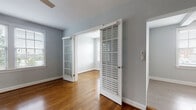 Located at 200 Rhode Island Avenue NE in Washington, DC, this single-floor residence offers a well-organized layout with a clean, contemporary aesthetic throughout. Rich hardwood flooring flows consistently across the living areas and bedrooms, lending warmth and continuity to the space. Walls are finished in a soft, neutral gray palette, creating a calm and inviting atmosphere.

The living area is generously proportioned, with an open sightline toward the kitchen, which is outfitted with dark espresso cabinetry, granite countertops, stainless steel appliances including a range, microwave, and dishwasher, and a white tile backsplash. A window allows natural light to fill the kitchen, enhancing its functional appeal.

The bedrooms feature hardwood floors, ceiling fans, and white plantation shutters that offer both privacy and light control. Each room benefits from multiple windows with views of the surrounding greenery. Connecting the rooms, wide doorways with louvered shutter doors add architectural character to the interior.

The bathroom is finished with large-format light tile flooring, a dark-tiled walk-in shower with a glass enclosure, and a vanity with dark countertops. A window provides natural ventilation. The overall layout is efficient and well-maintained, offering a comfortable urban residence in a convenient DC neighborhood.