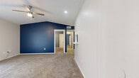 This single-story, two-bedroom, one-bathroom unit offers an efficiently organized layout across a comfortable footprint. The living room serves as the focal point, featuring vaulted ceilings, a ceiling fan, a white brick wood-burning fireplace, and a sliding glass door that admits natural light. A pass-through window connects the living area to the kitchen, enhancing the open feel between spaces.

The kitchen is outfitted with stone-look countertops, gray cabinetry, a subway tile backsplash, a stainless steel dishwasher, and light wood-look flooring. A window above the counter provides natural ventilation and light.

The primary bedroom includes vaulted ceilings, a ceiling fan, a large window, and access to a dedicated walk-in closet. The second bedroom features its own ceiling fan, a standard closet, and a window with natural light. Both bedrooms are finished with wall-to-wall carpet and bold gray-blue accent walls.

The bathroom is divided into two functional zones, with a toilet area separated from the vanity space, which features gray cabinetry, a wide mirror, and light wood-look flooring. A hallway connects the bedrooms and bathroom, completing the thoughtfully arranged floor plan.