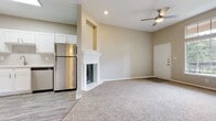 Located at 21480 Park Row Dr in Katy, TX, this single-story residence offers a well-designed, open layout that balances comfort and functionality. The living area serves as the heart of the home, highlighted by a classically trimmed fireplace and soaring vaulted ceilings that lend a sense of spaciousness. A ceiling fan provides year-round comfort, while soft, plush carpeting covers the main living and bedroom spaces, adding warmth underfoot. Wood-look luxury vinyl flooring transitions seamlessly into the kitchen and bathroom areas.

The kitchen is outfitted with crisp white shaker-style cabinetry, light quartz countertops, and a gray subway tile backsplash that adds subtle texture. Stainless steel appliances — including a refrigerator, electric range, and over-the-range microwave — complete the modern aesthetic, alongside a stainless undermount sink with a brushed nickel faucet.

A convenient built-in desk nook with upper cabinetry offers a dedicated workspace or study area just off the bedroom, which also provides direct access to the full bathroom. The bathroom features a soaking tub and shower combination with clean white tile surround, complemented by wood-look flooring. Neutral warm-beige tones throughout the home create a cohesive, move-in-ready ambiance.
