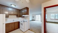 Located at 612 15th Place in Kenosha, WI, this one-bedroom, one-bathroom unit offers a practical and well-organized single-floor layout. The kitchen and dining area are combined into one functional space, featuring rich dark wood cabinetry that extends to the upper walls, white appliances including a electric coil range and full-size refrigerator, a single-basin sink, and light-toned tile flooring. The kitchen flows openly into the carpeted living room, which is bright and airy thanks to a large sliding glass door that leads to a private balcony with outdoor views. A wall-mounted air conditioning unit serves the living area. The bedroom offers a comfortable amount of space, carpeted flooring, a ceiling fan with light fixture, a window that lets in natural light, and direct access to a dedicated closet with shelving. In total, the unit includes three closets, providing generous storage throughout. Baseboard heating is present in the main living areas and bedroom. The clean white walls and neutral carpet tones throughout create a bright, move-in-ready atmosphere. This unit combines everyday practicality with a comfortable layout suited for single occupants or couples.