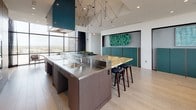 The Sky Lounge is a sophisticated, single-floor amenity space designed to maximize its elevated position through expansive floor-to-ceiling windows that frame panoramic views of the surrounding cityscape and river below. Natural light floods the interior throughout the day, creating a bright and inviting atmosphere across the open-plan layout.

The kitchen is a standout feature, outfitted with professional-grade stainless steel countertops and integrated sink, rich dark wood cabinetry with built-in double ovens, and a striking stone-topped bar with dark bar stools. A bold teal range hood serves as an architectural focal point overhead, while a sculptural multi-arm pendant light installation adds dramatic visual interest above the kitchen island.

Adjacent to the kitchen, the dining area accommodates a generous long wooden table surrounded by modern mixed seating, ideal for group gatherings or collaborative work sessions. Teal accent panels and curated artwork line the walls, adding depth and character to the space.

Tucked along the window wall, a quiet seating nook features two upholstered lounge chairs and a sculptural side table, offering an intimate setting for relaxed conversation while enjoying the sweeping views. Light hardwood flooring unifies the space, while access to an outdoor terrace further extends the Sky Lounge experience.