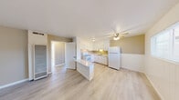Located at 1221 Vallejo Ave in Novato, California, this single-story, 2-bedroom, 1-bathroom residence offers a well-organized, efficient floor plan across its compact footprint. Light-toned luxury vinyl plank flooring runs throughout, lending a clean, cohesive look to every room.

The kitchen serves as a central feature of the home, outfitted with white cabinetry extending to the ceiling for ample storage, a white electric range, a stainless steel sink, and a full-size refrigerator. A peninsula counter provides additional prep space and visually connects the kitchen to the adjacent living area. A ceiling fan overhead adds practical comfort. Natural light enters through a window fitted with blinds, brightening the warm beige and white color palette.

The living room is open and simply appointed, with light walls, updated flooring, and a front entry door. Both bedrooms are comfortably sized, each featuring ceiling fans and windows that allow natural light. One bedroom includes a built-in closet with sliding doors, while the other features a wall-mounted air conditioning unit and a window with a view of surrounding greenery.

The bathroom is finished in an all-white palette, with a tiled tub-shower combination, a single-sink vanity with white cabinetry, a toilet, and a small frosted window for ventilation and privacy.