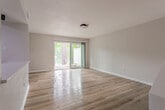 Located at 98 Lochview Dr in Newport News, Virginia, this two-floor home offers a well-organized layout with thoughtfully updated interiors. The kitchen is a standout feature, equipped with stainless steel appliances including a refrigerator, electric range, over-the-range microwave, and dishwasher. Light wood cabinetry pairs with a white quartz countertop and a tile backsplash, all set above warm hardwood flooring that extends throughout the main living areas. A built-in counter ledge provides additional workspace or casual dining space adjacent to the kitchen.

The living area is bright and open, highlighted by a large sliding glass door fitted with vertical blinds that invite natural light and provide access to the outdoors. Bedrooms are generously sized, each featuring hardwood floors and closet space, with vaulted ceilings adding to the airy feel in select rooms. The full bathroom includes a tub-shower combination with white tile surround and matte black fixtures, complemented by hardwood flooring.

A dedicated laundry area with plumbing hookups provides added convenience. The attached garage features a concrete floor and an automatic garage door, offering secure parking and additional storage. Throughout the home, neutral-toned walls and consistent hardwood flooring create a cohesive, clean aesthetic.