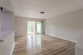 Located at 98 Lochview Dr in Newport News, Virginia, this two-floor home offers a well-organized layout with thoughtfully updated interiors. The kitchen is a standout feature, equipped with stainless steel appliances including a refrigerator, electric range, over-the-range microwave, and dishwasher. Light wood cabinetry pairs with a white quartz countertop and a tile backsplash, all set above warm hardwood flooring that extends throughout the main living areas. A built-in counter ledge provides additional workspace or casual dining space adjacent to the kitchen.

The living area is bright and open, highlighted by a large sliding glass door fitted with vertical blinds that invite natural light and provide access to the outdoors. Bedrooms are generously sized, each featuring hardwood floors and closet space, with vaulted ceilings adding to the airy feel in select rooms. The full bathroom includes a tub-shower combination with white tile surround and matte black fixtures, complemented by hardwood flooring.

A dedicated laundry area with plumbing hookups provides added convenience. The attached garage features a concrete floor and an automatic garage door, offering secure parking and additional storage. Throughout the home, neutral-toned walls and consistent hardwood flooring create a cohesive, clean aesthetic.