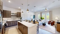 Located at 2351 Plaza Blvd in Richardson, TX, this well-appointed single-story residence offers one bedroom and two full bathrooms within a thoughtfully designed open-concept floor plan. The combined kitchen and living area forms the heart of the home, where wood-look flooring, recessed lighting, and crisp white walls create a clean, contemporary aesthetic. The kitchen is outfitted with dark walnut-toned cabinetry, quartz countertops, stainless steel appliances, a tiled backsplash, and a large center island with seating for multiple guests, illuminated by sleek pendant lights. The living area extends naturally from the kitchen and is bathed in natural light from floor-to-ceiling glass doors that open to a private balcony with outdoor views. The bedroom features large windows, generous natural light, and direct access to the primary bathroom, which includes a dual-sink vanity with wood cabinetry, quartz countertops, and a tub-shower combination. A second full bathroom provides additional convenience. Two well-organized walk-in closets with built-in shelving offer ample storage. A hallway connects the private quarters to the main living spaces, completing this refined and functional layout.