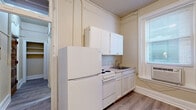 Located at 900 W Franklin St in Richmond, Virginia's historic Fan District, this two-bedroom, one-bathroom unit offers a compact yet efficiently arranged single-floor layout. The kitchen features white cabinetry extending to the ceiling, a coil-top electric range, a stainless steel sink, and light countertops, all set against warm neutral walls and wood-look flooring. Natural light enters through a side window, keeping the space bright and functional. A connecting hallway guides residents through the unit, maintaining a logical and accessible flow between rooms. The full bathroom is a notable highlight, featuring a classic clawfoot soaking tub, a separate toilet, and a window that allows natural light to fill the space. Gray wood-look vinyl flooring and neutral wall tones give the bathroom a clean, timeless character. Both bedrooms are finished with plush carpet and neutral walls. The generously sized primary bedroom benefits from a window with natural light, while the second bedroom includes access to a dedicated walk-in closet with built-in shelving — a practical storage solution. Crown molding, tall baseboards, and paneled doors throughout the unit reflect the traditional architectural character consistent with the historic Richmond neighborhood in which it resides.