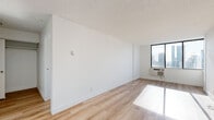 Located on Rue Prince Arthur Ouest in the heart of Montréal, this one-bedroom, one-bathroom unit offers a well-organized layout with clean, modern finishes. Light wood laminate flooring runs throughout the living spaces, complemented by crisp white walls and textured ceilings that lend a bright, airy feel.

The living room is a generous open space bathed in natural light from a large window framing striking city skyline views. The kitchen is efficiently designed with warm wood cabinetry extending floor to ceiling, white countertops, tile flooring, and stainless steel appliances including an electric range and refrigerator.

The bedroom is a well-proportioned retreat featuring corner windows that offer expansive panoramic views of the Montréal skyline, flooding the room with natural light. A built-in sliding-door closet provides practical storage.

The bathroom is finished to a high standard, featuring a vessel sink set on a white vanity with ample cabinetry for storage, a glass-enclosed shower, tile flooring, and brushed nickel hardware throughout. The cohesive white palette creates a clean, spa-like atmosphere.

Overall, the unit presents a compact yet functional living space with a consistent modern aesthetic, elevated by abundant natural light and impressive urban views.