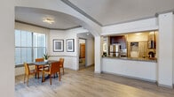 This single-story, one-bedroom, one-bathroom residence offers a thoughtfully designed open-concept floor plan that maximizes its generous living area. Light-toned hardwood-style flooring flows throughout the main living spaces, complementing the bright, neutral color palette and creating a cohesive, airy atmosphere.

The combined living, dining, and kitchen area forms the heart of the home. The living room features a ceiling fan, large windows with natural light, and a sliding glass door leading to an outdoor patio. An elegant arched architectural detail defines the transition into the dining space. The kitchen is outfitted with rich dark-wood cabinetry, granite countertops, stainless steel appliances including a refrigerator, range, and microwave, a subway tile backsplash, and a peninsula that opens to the dining area.

The bedroom is a comfortable, well-proportioned retreat with plush carpeting, a ceiling fan, and a window that invites natural light. A dedicated closet provides ample storage. The bathroom features a dark-wood vanity with granite countertops and a backlit mirror.

Additional highlights include a dedicated closet, and an attached single-car garage with an automatic opener. The space combines functional design with upscale finishes throughout.