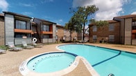The pool area serves as a central outdoor amenity within the residential community, offering both a full-sized swimming pool and an adjoining spa. The pool is finished with classic blue tile accents along its edges and features clearly marked depth indicators, providing practical safety information for users. The surrounding pool deck is finished in a textured aggregate surface, offering slip-resistant footing and space for lounge seating.

A wrought iron perimeter fence encloses the pool area, providing security while maintaining open sightlines to the surrounding grounds and mature shade trees that contribute to a comfortable outdoor atmosphere. Picnic seating is available within the fenced area, supporting casual outdoor gatherings.

The broader community grounds feature multi-story buildings constructed with a combination of brick and horizontal lap siding in neutral tones. Exterior stairways with metal railings provide access between levels. Ground-level storage areas are situated beneath the stairwells, and a playground area is visible on the property grounds. The exterior siding is painted in a light, clean tone. Overall, the outdoor spaces are designed to support day-to-day community living with functional recreational and common-area amenities.
