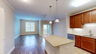 Located at 1 Millers Way in Simsbury, CT, this well-appointed 2-bedroom, 3-bathroom residence offers a thoughtfully designed single-floor layout with a comfortable, functional flow throughout. The open-concept kitchen and living area serves as the heart of the home, showcasing rich warm-toned cabinetry, granite countertops, a subway tile backsplash, and stainless steel appliances including a range, microwave, refrigerator, and dishwasher. A central kitchen island provides additional prep and seating space, while pendant lighting adds a refined touch. Hardwood-style flooring runs through the main living and kitchen areas, lending warmth and easy maintenance. The spacious primary bedroom features a generous footprint, neutral carpeting, and access to its own bathroom. The second bedroom is well-sized with plush carpet and natural light from large windows with views of the surrounding community. Three bathrooms are distributed throughout the unit, including one outfitted with a soaking tub, tiled shower surround, and accessibility grab bars. Bathrooms feature light wood vanities and tile flooring. A dedicated closet and hallway complete the layout, contributing to the home's organized and accessible design. Soft neutral wall tones and crown molding details create a clean, cohesive aesthetic throughout.