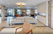 This expansive 4,240 square foot lobby, located at 1554 Midway Pkwy in Saint Paul, Minnesota, showcases a harmonious blend of modern design and industrial chic aesthetics. The single-floor space is characterized by its open layout, combining various functional areas seamlessly.

The lobby features exposed brick walls, offering a rustic charm that contrasts beautifully with the polished concrete floors and contemporary furnishings. Large windows allow ample natural light to flood the space, enhancing the airy atmosphere.

Multiple seating arrangements cater to different needs, from casual lounge areas with plush sofas and armchairs to more formal dining setups with sleek tables and chairs. A striking red pool table adds a pop of color and recreational opportunity to the space.

Lighting is a key design element, with a mix of recessed ceiling lights, pendant lamps, and statement fixtures like the circular LED chandelier, creating a warm and inviting ambiance. The lobby also incorporates modern amenities, including a fireplace and various entertainment options.

Thoughtful details such as area rugs, potted plants, and artwork on the walls contribute to a cohesive and inviting environment. The space seamlessly transitions between different functional areas, from the entrance with its glass doors to the various seating and activity zones, making it ideal for socializing, relaxation, or work.

This versatile lobby space effectively combines comfort, style, and functionality, creating an impressive and welcoming environment for residents or visitors.