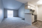 This single-floor, 2-bedroom, 1-bathroom residence offers a thoughtfully arranged layout that maximizes its comfortable footprint. The living area immediately impresses with dramatically vaulted ceilings that lend a sense of openness and airiness well beyond what its floor plan suggests. Neutral gray walls and plush carpeting throughout the main living and bedroom areas create a cohesive, understated aesthetic. A sliding glass door floods the living space with natural light and provides outdoor access.

The kitchen is designed in a galley configuration with wood-look vinyl flooring, white cabinetry, granite-style countertops, and a breakfast bar that connects it to the living area. Stainless steel appliances, including a refrigerator, electric range, and dishwasher, complete the functional space.

Both bedrooms are carpeted and receive natural light through large windows with blinds. The primary bedroom includes a ceiling fan and a walk-in closet, while the second bedroom also offers a ceiling fan fixture. The shared full bathroom features a vessel-style sink, granite-style countertop vanity, dark hardwood-look flooring, a large mirror with lighted surround, and a full tub-shower combination.