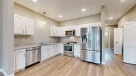 Located at 4340 Belden Greens Cir NW in Canton, Ohio, this single-floor, 2-bedroom, 2-bathroom home offers a clean, modern aesthetic with thoughtfully selected finishes throughout. The open-concept living and kitchen area is anchored by light hardwood-style flooring and neutral warm-gray walls, creating a bright and cohesive atmosphere. Recessed lighting illuminates the space, complemented by pendant lighting above the kitchen area.

The kitchen is a standout feature, equipped with white shaker-style cabinetry, granite countertops, and a full suite of stainless steel appliances including a French door refrigerator, gas range, built-in microwave, and dishwasher. The entry foyer benefits from vaulted ceilings and a sidelight-flanked front door that draws in natural light.

The bedrooms are carpeted for comfort, with the primary bedroom offering a ceiling fan, sliding glass door with outdoor views, and access to a spacious walk-in closet with wire shelving. The second bedroom also includes a dedicated closet. Both bathrooms are finished with granite-topped white vanities and wood-look tile flooring. The primary bathroom features a wide vanity with ample drawer storage and a wall-mounted cabinet for additional organization.