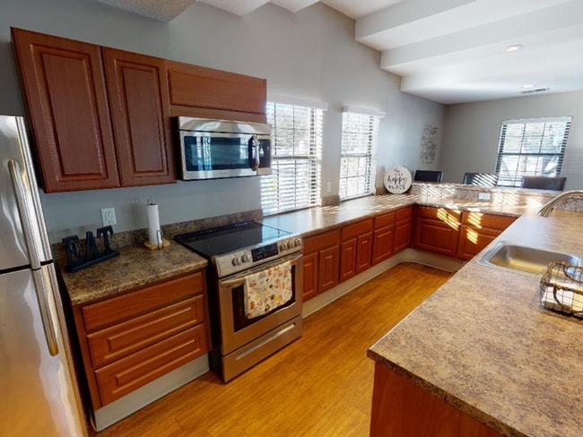 Large windows allow sunlight to stream in, highlighting sleek countertops and newer stainless steel appliances that offer both style and convenience. - Central Park Place