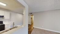 This single-floor residence offers a practical and well-organized layout designed for comfortable everyday living. The entry opens into a combined living and dining area finished with plush carpeting, transitioning to durable wood-look flooring in the kitchen and hallway zones. A textured popcorn ceiling runs throughout the unit, adding a classic character to the interior.

The kitchen is efficiently designed with white shaker-style cabinetry, white countertops, and a full suite of black appliances including an electric coil range, over-the-range microwave, refrigerator, and dishwasher. A skylight-style overhead fixture brightens the space, while a pass-through window connects the kitchen to the living area, enhancing the open feel. The living room benefits from a large sliding glass door fitted with vertical blinds, allowing generous natural light to filter in.

The bedroom is a comfortable, carpeted retreat featuring a ceiling fan with light kit and a window dressed with horizontal blinds that invites natural light while maintaining privacy. The bathroom is clean and functional, equipped with a shower-tub combo, updated fixtures, and wood-look flooring. A dedicated hallway connects the main areas, providing a logical and efficient flow throughout the space.