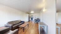 Located at 1725 N Park Ave in Tucson, AZ, this single-floor unit offers a well-organized layout across two bedrooms, a combined kitchen and living room, a hallway, and a full bathroom. Warm hardwood flooring runs throughout the space, lending a cohesive and inviting feel to every room.

The open kitchen and living area serves as the heart of the unit. The kitchen is outfitted with white shaker-style cabinetry, granite-look countertops, and a full suite of stainless steel appliances including a refrigerator, range, dishwasher, and range hood. A dining table with stools provides a casual eating area adjacent to the kitchen. The living room offers ample space for seating, with a window that brings in natural light and provides a view of the surrounding neighborhood.

Both bedrooms are comfortably sized with clean white walls and the same warm hardwood flooring found throughout. Each room provides enough space for a bed and additional furnishings such as a dresser or side table.

The bathroom features a clean, all-white walk-in shower with bright finishes, maintaining the unit's straightforward and functional design aesthetic. A hallway connects the various rooms, contributing to the efficient flow of the layout. Overall, the unit presents a clean, practical living environment well-suited to Tucson's urban setting.