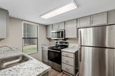 This contemporary apartment, located at The Ellington 105, offers 870 square feet of thoughtfully designed living space. The floor plan includes three bedrooms, two full bathrooms, a combined kitchen and living room, a hallway, laundry area, and closet space.

The kitchen is a highlight, featuring sleek gray cabinetry, granite countertops, and stainless steel appliances. The galley-style layout maximizes efficiency, with ample storage and counter space. A window above the sink allows natural light to flood the area.

The living room is spacious and bright, with large windows and durable wood-look flooring. This open-concept space flows seamlessly from the kitchen, creating an ideal area for entertaining or relaxing.

The bedrooms are well-proportioned, with the primary bedroom measuring 160 square feet. Each bedroom features plush carpeting and a built-in closet for storage. Windows in the bedrooms provide natural light and views of the surroundings.

Both bathrooms have been updated with modern fixtures, including vanities with granite countertops and large mirrors. One bathroom showcases a combination tub/shower, while the other appears to have a stand-alone shower.

Throughout the apartment, neutral tones create a calm and versatile backdrop for any decor style. The unit also includes an in-unit laundry area, adding convenience to daily life.

Overall, this apartment offers a contemporary living space with updated finishes and a practical layout, ideal for those seeking a modern urban lifestyle.