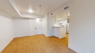 Located at 1400 Long Beach Boulevard in Long Beach, California, this two-bedroom, one-bathroom unit offers a clean and contemporary living environment across a single floor. The interior is finished with warm hardwood-style flooring that runs consistently throughout every room, complemented by crisp white walls and white baseboards that create a bright, cohesive aesthetic.

The living room is an open, airy space anchored by a glass patio door fitted with vertical blinds, allowing natural light to filter in while providing views of the surrounding greenery. A peninsula counter connects the living area to the kitchen, which features a galley-style layout with white shaker cabinetry, ample counter space, a stainless steel refrigerator, a range, a dishwasher, and a skylight overhead that keeps the space well-lit.

Both bedrooms are simply designed with white walls, clean lines, and the same warm flooring. The second bedroom includes a window with an outdoor view, adding natural light to the space. The bathroom is functional and neatly finished, equipped with a full tub-shower combination, grab bars, and a toilet, all set against white walls and matching flooring. The overall layout is efficient and well-organized, making practical use of the available space throughout.
