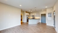 Located at 5 Ledge Drive in Niskayuna, NY, this single-floor, one-bedroom, one-bathroom residence offers a thoughtfully designed layout with contemporary finishes throughout. The open-concept kitchen serves as the heart of the home, featuring sleek white cabinetry reaching toward the ceiling, dark granite countertops, a large peninsula with an undermount sink and modern pull-down faucet, and a full suite of stainless steel appliances including a French door refrigerator, electric range, and built-in microwave. A textured tile backsplash adds visual interest, while pendant lighting over the peninsula and recessed ceiling lights provide layered illumination. Light hardwood-style flooring extends through the main living areas, creating a warm, cohesive feel. The bedroom offers plush carpeting, a large window with exterior views, and a distinctive sliding barn-style door that adds a modern-industrial design touch. The bathroom is finished with a walk-in glass-enclosed shower featuring white subway tile walls, herringbone marble tile flooring, a built-in bench, and brushed nickel fixtures. An attached garage with overhead door opener and clean concrete flooring completes this well-appointed residence.