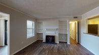 Located at 321 Calibre Chase Dr in Raleigh, NC, this single-story home offers a thoughtfully arranged layout with a comfortable blend of practical features and classic details. The living room serves as the focal point of the home, showcasing a fireplace flanked by symmetrical built-in shelving units — ideal for display or storage. Crown molding accents the space, while dark hardwood-style flooring runs throughout the main living areas, adding warmth and visual continuity. A window with blinds allows natural light to fill the room. The open sightlines from the living area extend toward a separate dining space and into the kitchen, which is connected via a pass-through opening. The kitchen is equipped with a stainless steel gas range, white cabinetry with brushed nickel hardware, granite-look countertops, and direct access to a utility area housing the electrical panel. Bedroom spaces include rooms with plush carpet flooring and large windows framing outdoor greenery, offering a quiet, natural atmosphere. The bathroom features a full tub and shower combination with clean white surrounds. Throughout the home, neutral gray tones, consistent trim work, and closet storage contribute to a cohesive and move-in ready environment.
