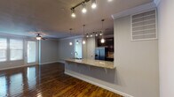 This single-floor, 2-bedroom, 2-bathroom residence combines modern finishes with a functional, open layout. Rich hardwood flooring flows throughout the space, complemented by crown molding and ceiling fans in the main living areas.

The kitchen is a standout feature, equipped with dark espresso cabinetry, granite countertops, a tile backsplash, and a full suite of stainless steel appliances including a French door refrigerator, electric range, and built-in microwave. A peninsula breakfast bar with pendant lighting provides additional seating and connects the kitchen to the open living area. Track lighting further illuminates the space.

The entryway features textured walls, an arched decorative niche, and a large built-in closet. Both bedrooms offer ceiling fans, crown molding, and hardwood floors. The primary bedroom includes a walk-in closet and a spacious en-suite bathroom with dual granite-topped vanities, a separate glass-enclosed shower, and a soaking tub with tile surround. The secondary bathroom features a tub-shower combo with tile surround and a granite vanity.