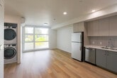 Located at 2650 Telegraph Ave in Berkeley, California, this modern 1-bedroom, 1-bathroom unit offers a thoughtfully designed layout that maximizes its compact footprint. Light hardwood flooring flows throughout the space, complementing the clean white walls and recessed lighting that give the interior a bright, contemporary feel.

The open-concept living and kitchen area forms the heart of the unit. The kitchen is well-appointed with flat-front gray cabinetry extending to the ceiling for ample storage, a vertical tile backsplash, white quartz countertops, and a full suite of stainless steel appliances including a refrigerator, electric range, microwave, and dishwasher. A large picture window in the living area frames lush, greenery-filled outdoor views and floods the space with natural light. A wall-mounted mini-split system provides efficient climate control.

A convenient in-unit stacked washer and dryer is neatly tucked within a closet off the main living area. The bedroom offers a dedicated and private retreat, while the bathroom features a modern gray vanity with a white countertop, wood-look flooring, and a glass-enclosed shower. A separate closet provides additional storage. The overall aesthetic is clean, minimal, and move-in ready.