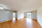Located at 2224 Village Green Pkwy in Chesterfield, MO, this one-bedroom, one-bathroom unit offers a well-organized single-floor layout designed for comfortable everyday living. The living room serves as the heart of the space, featuring warm hardwood-style flooring, crisp white walls, and a textured ceiling. A sliding glass door floods the room with natural light and opens to a private balcony overlooking pleasant outdoor scenery, creating a bright and airy atmosphere throughout. The galley-style kitchen is efficiently designed with dark cabinetry, light countertops, a white tile backsplash, and black appliances including a refrigerator and range. A window above the sink provides additional natural light, making the kitchen feel open despite its compact footprint. The bedroom is a comfortable retreat, finished with plush carpeting and multiple closet doors offering generous storage. A window with blinds brings in natural light while maintaining privacy. The bathroom features a full tub-shower combination with white tile surround, complemented by earthy tile flooring and wall-mounted cabinetry for added storage. Overall, the space presents a clean, functional design with consistent finishes throughout, making it a practical and inviting home in the Village Green community.